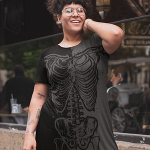 K&ouml;nnte beinhalten: Schwarzes und graues Kleid mit Skelettmuster. Das kurz&auml;rmelige Kleid hat einen Rundhalsausschnitt und einen Saum in Kniel&auml;nge. Das detaillierte Skelettmuster erzeugt einen gotischen Stil.