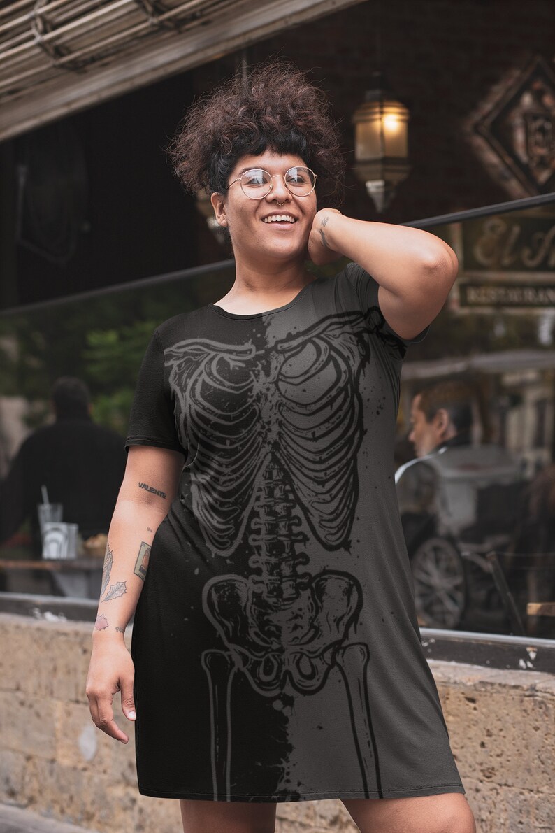 K&ouml;nnte beinhalten: Schwarzes und graues Kleid mit Skelettmuster. Das kurz&auml;rmelige Kleid hat einen Rundhalsausschnitt und einen Saum in Kniel&auml;nge. Das detaillierte Skelettmuster erzeugt einen gotischen Stil.