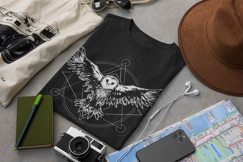 K&ouml;nnte beinhalten: Schwarzes T-Shirt mit einem wei&szlig;en Aufdruck einer Eule, die in einem geometrischen Muster fliegt.
