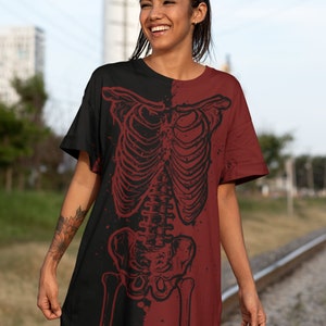 K&ouml;nnte beinhalten: Ein schwarzes und maroonfarbenes T-Shirt-Kleid mit einem Skelett-Motiv auf der Vorderseite. Das Skelett ist in Schwarzwei&szlig; gehalten und im Used-Look umrandet.