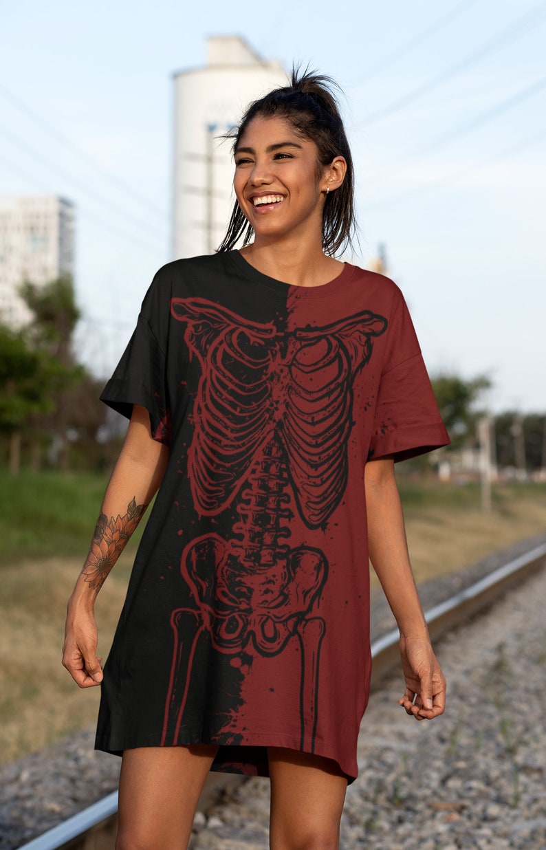 K&ouml;nnte beinhalten: Ein schwarzes und maroonfarbenes T-Shirt-Kleid mit einem Skelett-Motiv auf der Vorderseite. Das Skelett ist in Schwarzwei&szlig; gehalten und im Used-Look umrandet.