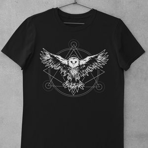 K&ouml;nnte beinhalten: Schwarzes T-Shirt mit einem wei&szlig;en Grafikdruck eines fliegenden Eulen innerhalb eines geometrischen Kreises.