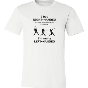 May include: White t-shirt with black text that reads "I bat RIGHT-HANDED to give everyone else a chance. I'm really LEFT-HANDED". The text is accompanied by three black silhouettes of baseball players.