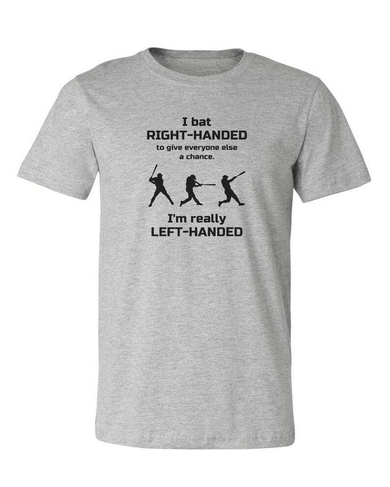 May include: Gray t-shirt with a baseball-themed design. The text reads "I bat RIGHT-HANDED to give everyone else a chance. I'm really LEFT-HANDED".