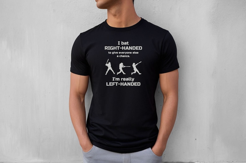 May include: Black t-shirt with a white graphic that says "I bat RIGHT-HANDED to give everyone else a chance. I'm really LEFT-HANDED". The graphic also includes three stick figures of baseball players.
