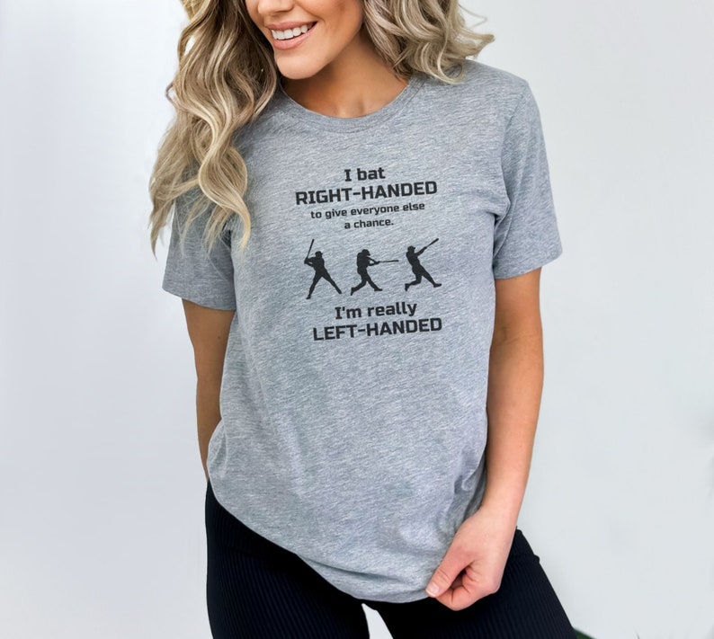 May include: Gray t-shirt with a black graphic that says "I bat RIGHT-HANDED to give everyone else a chance. I'm really LEFT-HANDED". The graphic also includes three baseball players.