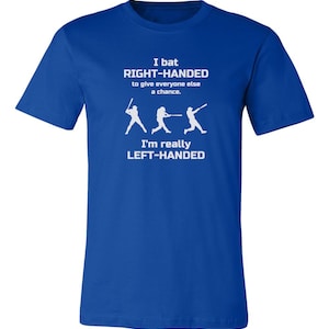 May include: A royal blue t-shirt with white text that reads "I bat RIGHT-HANDED to give everyone else a chance. I'm really LEFT-HANDED". The text is accompanied by a graphic of three baseball players batting.