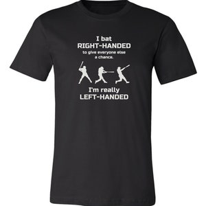May include: Black t-shirt with white text that reads "I bat RIGHT-HANDED to give everyone else a chance. I'm really LEFT-HANDED". The text is accompanied by three white silhouettes of baseball players batting.