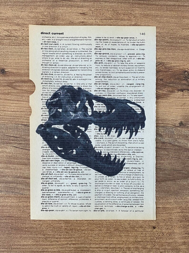 May include: A black and white illustration of a dinosaur skull is silhouetted on a vintage dictionary page. The image is a unique blend of art and literature, perfect for a home decor item.