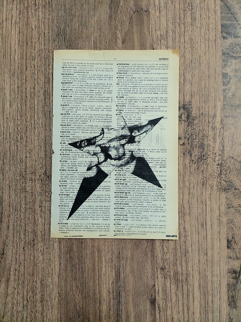 Pu&ograve; includere: Una pagina rettangolare tratta da un vecchio dizionario con carta invecchiata color bianco sporco e testo stampato in nero. Una grande stella nera a cinque punte &egrave; stampata sopra il centro del testo, con un aspetto usurato e strutturato.