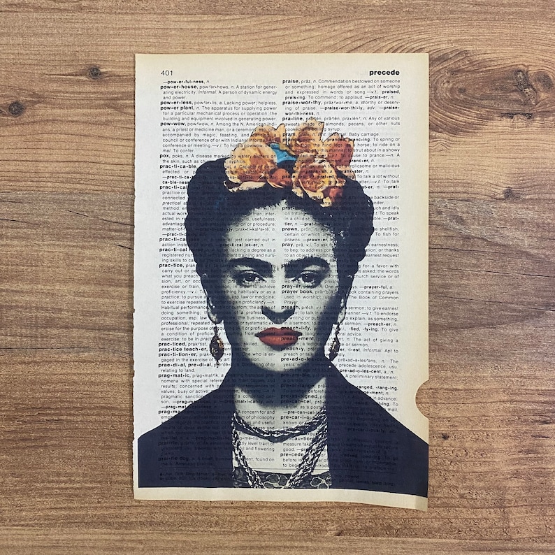 Op de afbeelding: Een zwart-wit portret van Frida Kahlo met een bloemenkrans op haar hoofd. Het portret is gedrukt op een vintage woordenboekpagina met de woorden "practice" en "precede" zichtbaar.
