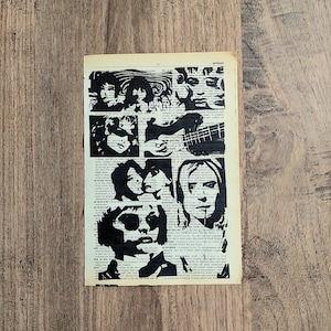 Pu&ograve; includere: Una pagina rettangolare tratta da un dizionario vintage con illustrazioni serigrafate in inchiostro nero raffiguranti diversi volti e una chitarra. Il testo della pagina &egrave; visibile dietro le audaci stampe grafiche nere ad alto contrasto.