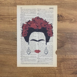 Op de afbeelding: Een digitale kunstprint met een portret van Frida Kahlo met een rode bloemenkrans. Het portret is gesuperponeerd op een vintage woordenboekpagina met het woord "plateful" dat is gemarkeerd.