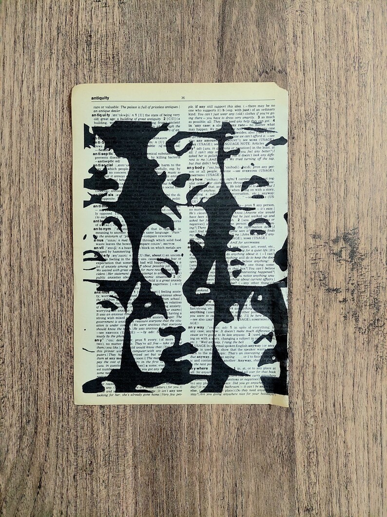 Pu&ograve; includere: Un foglio rettangolare di carta da dizionario color bianco sporco con una audace illustrazione a inchiostro nero di diversi volti umani sovrapposti. Il testo stampato della pagina del dizionario rimane visibile sotto le forme nere dei volti.