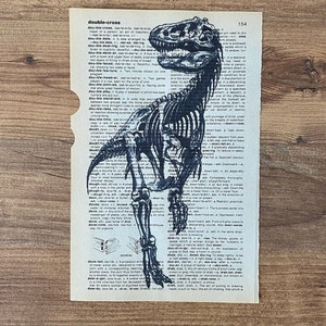 May include: An illustration of a Tyrannosaurus Rex skeleton is printed on a vintage dictionary page. The page has a torn edge and the word "double-cross" is visible.