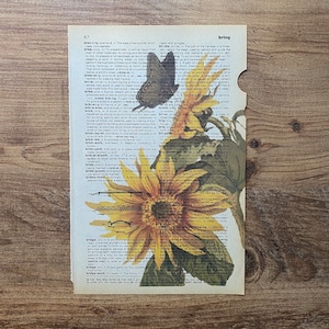 May include: A vintage dictionary page with a yellow sunflower and a butterfly on it. The page features the words "brew", "briar", "bribe", "brick", "bride", and "bridge".