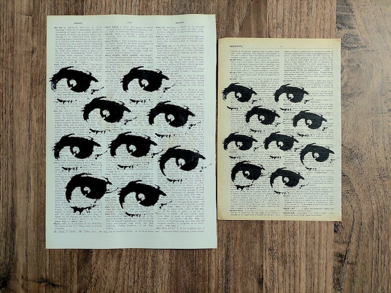 Pu&ograve; includere: Due pagine rettangolari tratte da un dizionario vintage con illustrazioni a inchiostro nero di molteplici occhi. La pagina sinistra, pi&ugrave; grande, contiene otto occhi dipinti, mentre la pagina destra, pi&ugrave; piccola, ne mostra sei su testo stampato.
