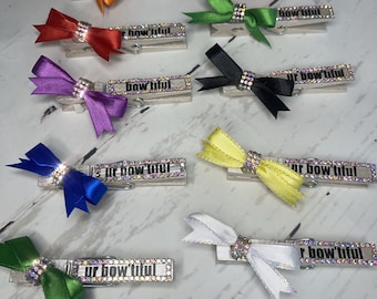May include: Assortment of colorful hair clips with bows and rhinestones. Each clip features the text "ur bow'tiful" in black lettering.