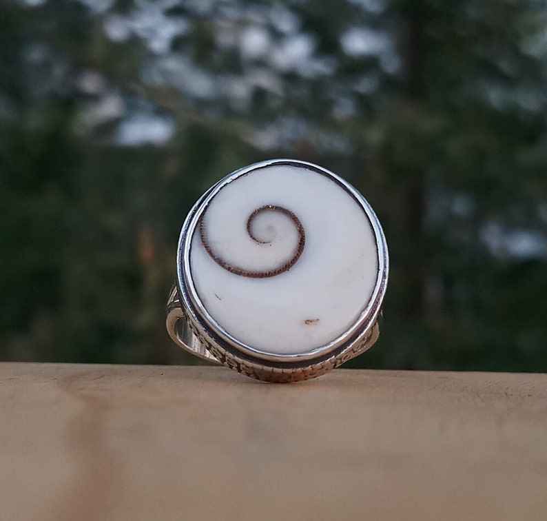 Op de afbeelding: Een zilveren ring met een witte en bruine schelp inlay met een spiraalvormig ontwerp.