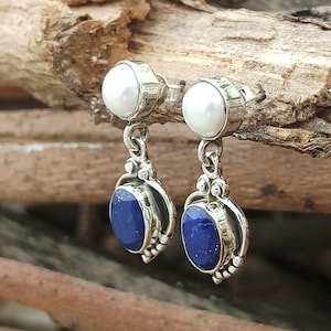Pode incluir: Um par de brincos de prata com uma p&eacute;rola branca e uma pedra de l&aacute;pis-laz&uacute;li azul.