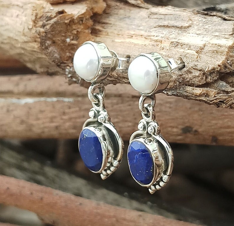 Pode incluir: Um par de brincos de prata com uma p&eacute;rola branca e uma pedra de l&aacute;pis-laz&uacute;li azul.