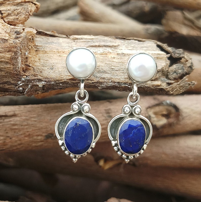 Pode incluir: Brincos de prata esterlina com uma pedra de lapis-laz&uacute;li azul e uma p&eacute;rola branca.
