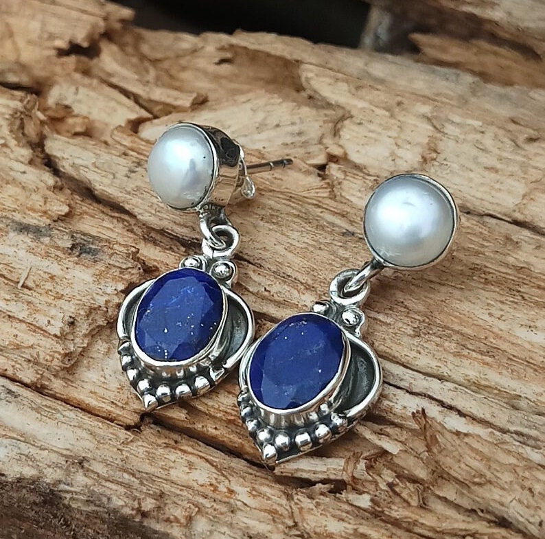 Pode incluir: Brincos de prata esterlina com uma pedra de lapis-laz&uacute;li azul e uma p&eacute;rola branca.