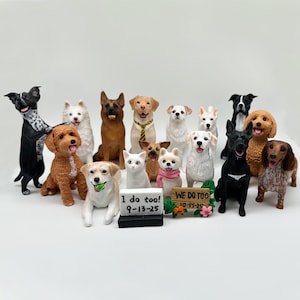 May include: A collection of dog figurines in various breeds and colors, including a black and white dog, a brown dog, and a white dog. Some dogs have accessories. Two signs read "I do too! 9-13-25" and "WE DO TOO 10-15-25".