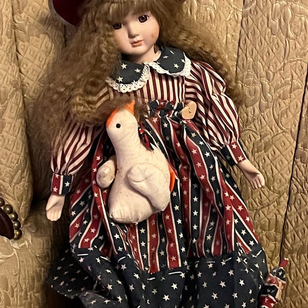 Muñeca de Porcelana con vestido y capota rojos.