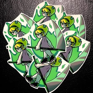 May include: A collection of stickers featuring a cartoon character with yellow hair, a purple dress, and black shoes. The character is holding a scythe with a green and brown design. The background has a green and white design. The text "FOWL-TOWN" is on the scythe.