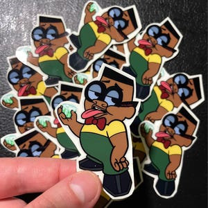 Puede incluir: Una colección de pegatinas de dibujos animados con un personaje de piel morena con gafas grandes, una pajarita roja y un atuendo verde y amarillo. El personaje sostiene un objeto verde y saca la lengua.