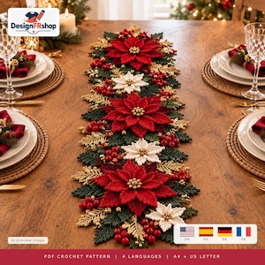 Puede incluir: Un camino de mesa de ganchillo con flores de pascua rojas y blancas, hojas de color verde oscuro y detalles de follaje dorado. El diseño incluye racimos de pequeñas bayas rojas y cuentas doradas dispuestas en un patrón decorativo largo.