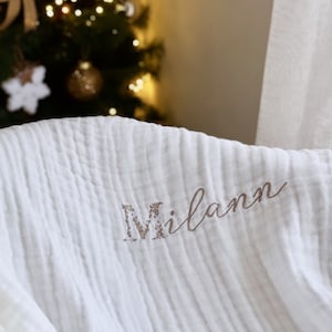 Pu&ograve; includere: Coperta per neonato in mussola bianca con il nome "Milan" ricamato in corsivo marrone.