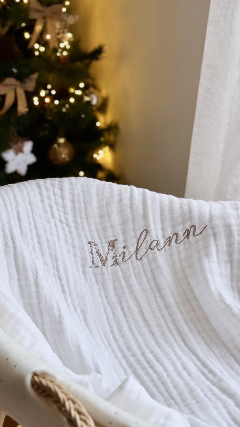 Pu&ograve; includere: Coperta per neonato in mussola bianca con il nome "Milan" ricamato in corsivo marrone.