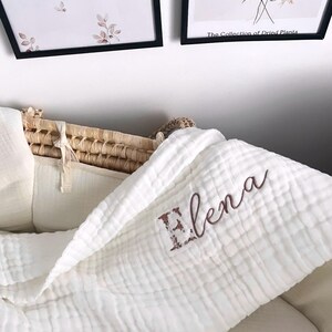 Pu&ograve; includere: Coperta per neonato in mussola bianca con il nome "Elena" ricamato in marrone.