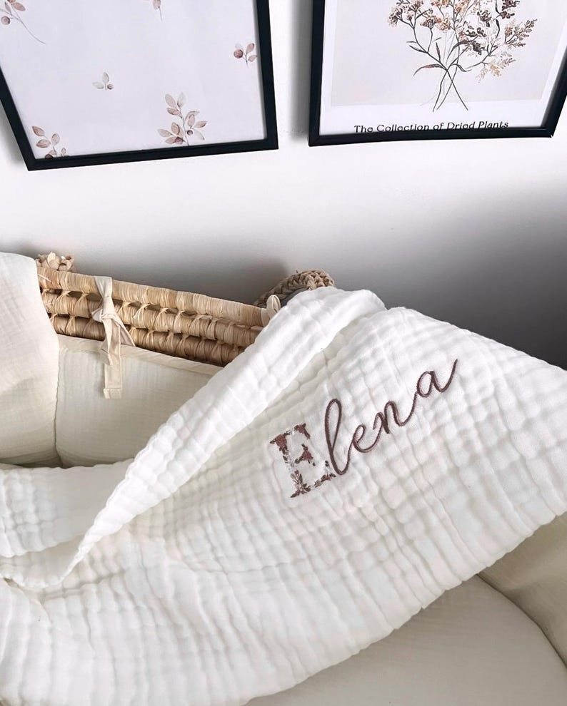 Pu&ograve; includere: Coperta per neonato in mussola bianca con il nome "Elena" ricamato in marrone.
