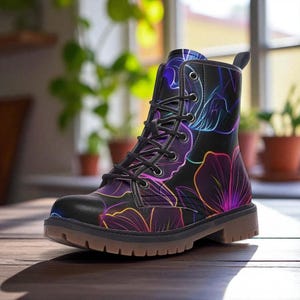 Puede incluir: Bota de combate negra con un diseño floral en tonos morados, azules y amarillos. La bota tiene cierre de cordones y suela marrón. El estampado floral es un diseño de neón.