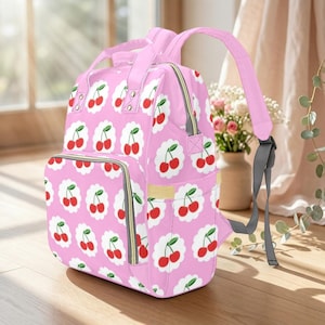 Op de afbeelding: Een witte keramische mok met een zwart handvat en de tekst "But First, Coffee" in een vetgedrukte, zwarte letter. De mok is gevuld met een donkere vloeistof, waarschijnlijk koffie, en staat op een lichtgekleurd oppervlak.