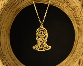 Pode incluir: Um colar com pingente dourado com um design estilizado de teia de aranha. O pingente é suspenso por uma corrente delicada. O colar é exibido em um fundo de madeira texturizada marrom claro com um fundo escuro.