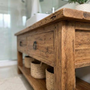 A rustic wooden bathroom vanity featuring two drawers with dark metal ring pulls, and an open bottom shelf for storage. The vanity is made of reclaimed wood with a natural finish.
Rustic Bathroom Vanity,  Wood Bathroom Vanity, Custom Single Sink Vanity, Unique Reclaimed Farmhouse Vanity with Storage