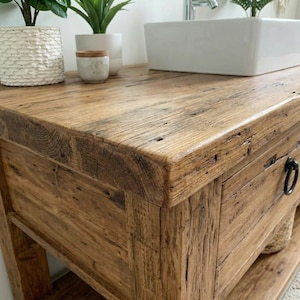 A rustic wooden bathroom vanity featuring two drawers with dark metal ring pulls, and an open bottom shelf for storage. The vanity is made of reclaimed wood with a natural finish.
Rustic Bathroom Vanity,  Wood Bathroom Vanity, Custom Single Sink Vanity, Unique Reclaimed Farmhouse Vanity with Storage