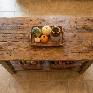 A rustic wooden kitchen table with a lower shelf. The table's surface has a natural, weathered appearance, showcasing the wood grain. Reclaimed Wood Kitchen Island , Farmhouse Rustic Kitchen Island with Shelf, Counter Height Dining Table, butcher block island