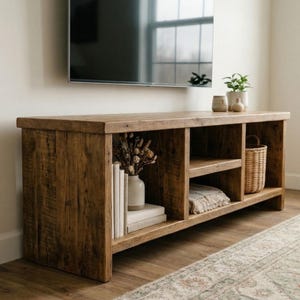 A rustic wooden media console featuring a natural brown finish with visible wood grain. The unit has open shelves. TV Stand with Vinyl Record Storage