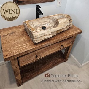 A rustic wooden bathroom vanity featuring two drawers with dark metal ring pulls, and an open bottom shelf for storage. The vanity is made of reclaimed wood with a natural finish.
Rustic Bathroom Vanity,  Wood Bathroom Vanity, Custom Single Sink Vanity, Unique Reclaimed Farmhouse Vanity with Storage