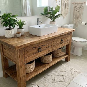 A rustic wooden bathroom vanity featuring two drawers with dark metal ring pulls, and an open bottom shelf for storage. The vanity is made of reclaimed wood with a natural finish.
Rustic Bathroom Vanity,  Wood Bathroom Vanity, Custom Single Sink Vanity, Unique Reclaimed Farmhouse Vanity with Storage