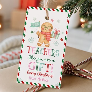 May include: A rectangular gift tag featuring a gingerbread man illustration, with the text "TEACHERS like you are a GIFT!" and "Merry Christmas from Madison". The tag has a red and green border and is attached to a wrapped gift.