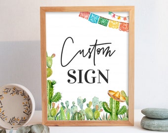 May include: A framed sign with the words "Custom SIGN" in black script. The sign features watercolor illustrations of cacti, a sombrero, and colorful papel picado banners. The frame is made of light-colored wood.
