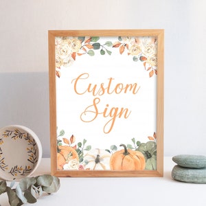 Puede incluir: Un cartel imprimible enmarcado con fondo blanco y borde floral. El cartel dice "Custom Sign" en texto naranja. El borde floral presenta rosas blancas, hojas verdes y calabazas naranjas.