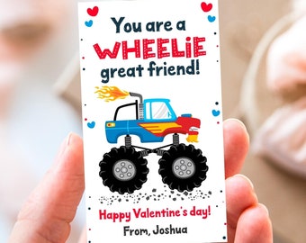 May include: A white card featuring a blue monster truck with red flames and red wheels. The card reads "You are a WHEELIE great friend!" and "Happy Valentine's day! From, Joshua".