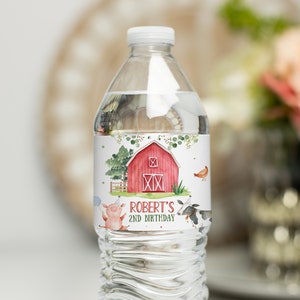 Puede incluir: Etiqueta de botella de agua con un granero rojo, árboles verdes y animales de granja. La etiqueta dice "Robert's 2nd Birthday".